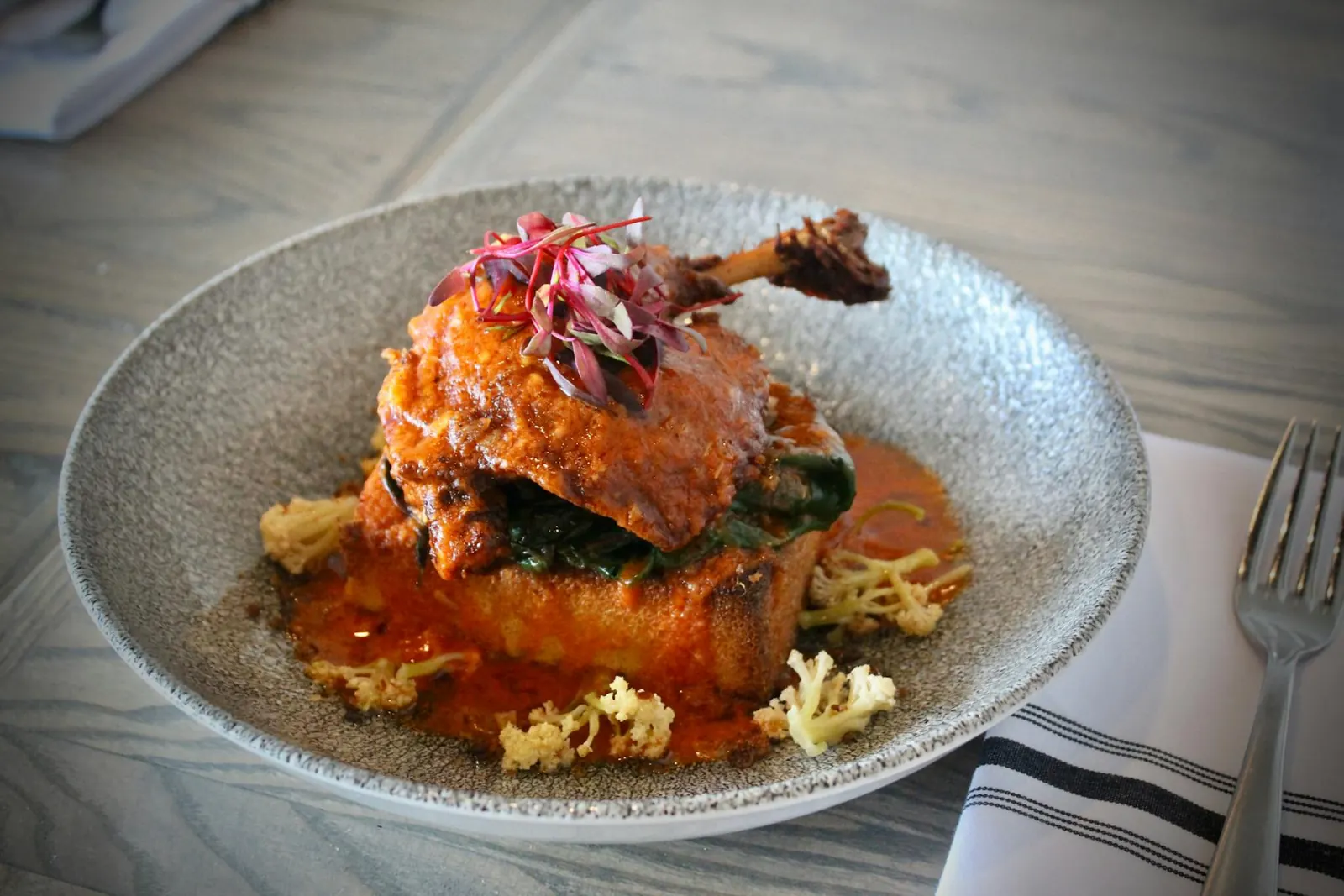 Crispy confit duck leg plated with sauce