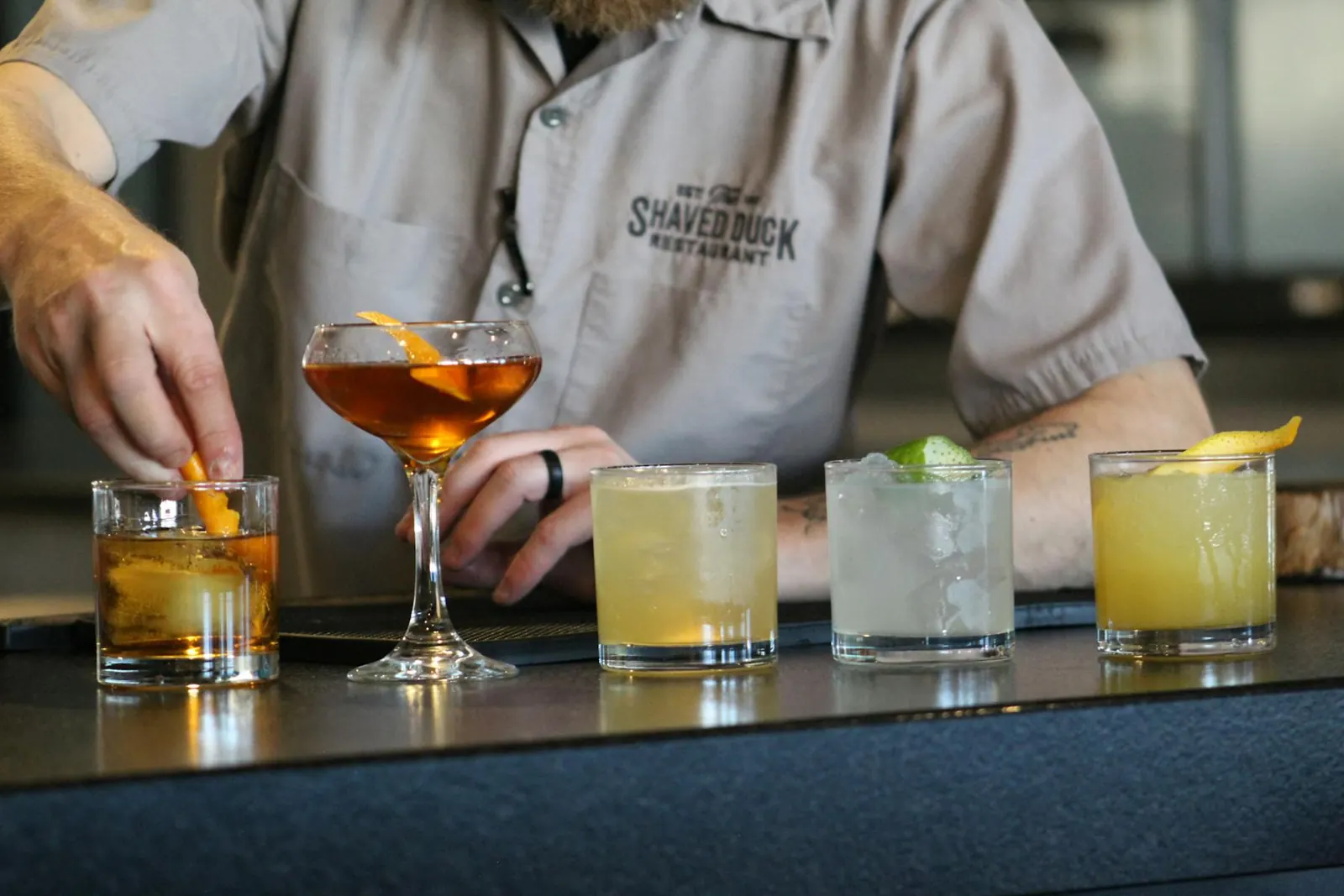 A bartender finishing a row of craft cocktails