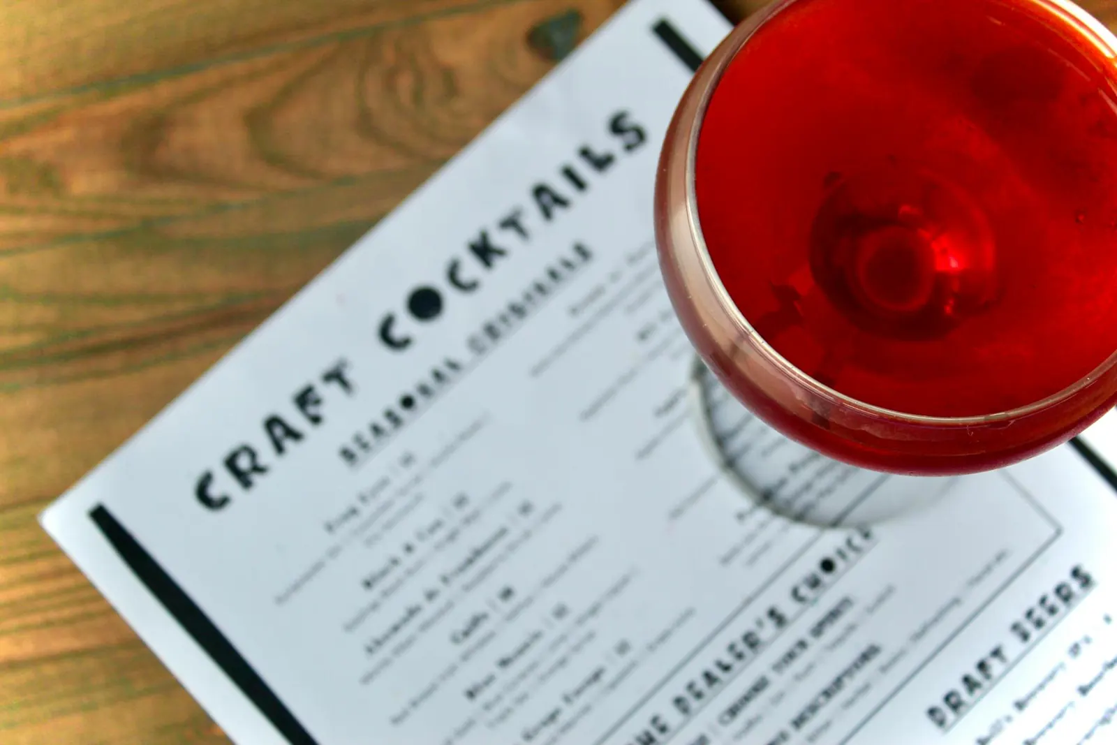 A red craft cocktail resting on the craft cocktails menu