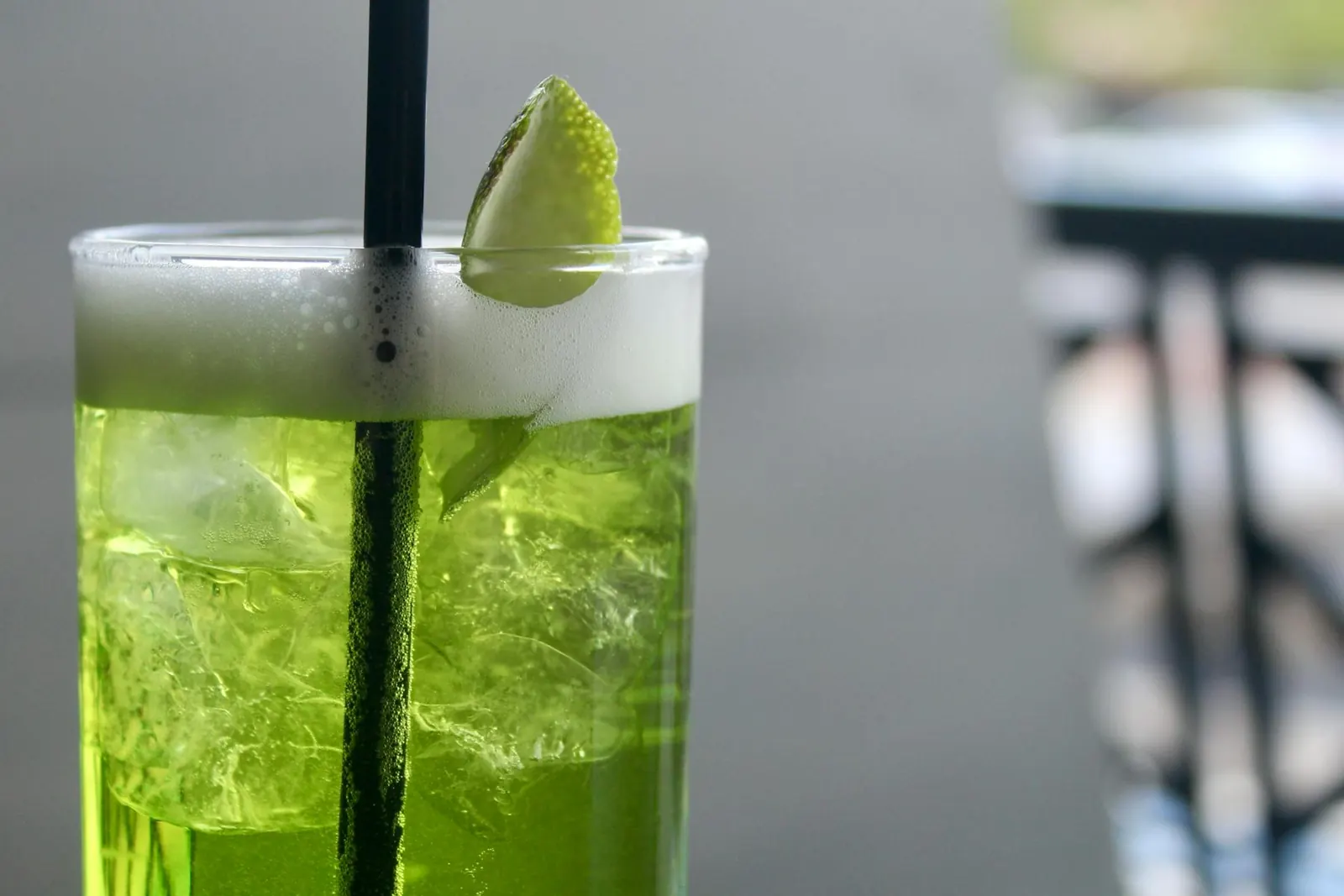 A bright green craft cocktail with a lime wheel