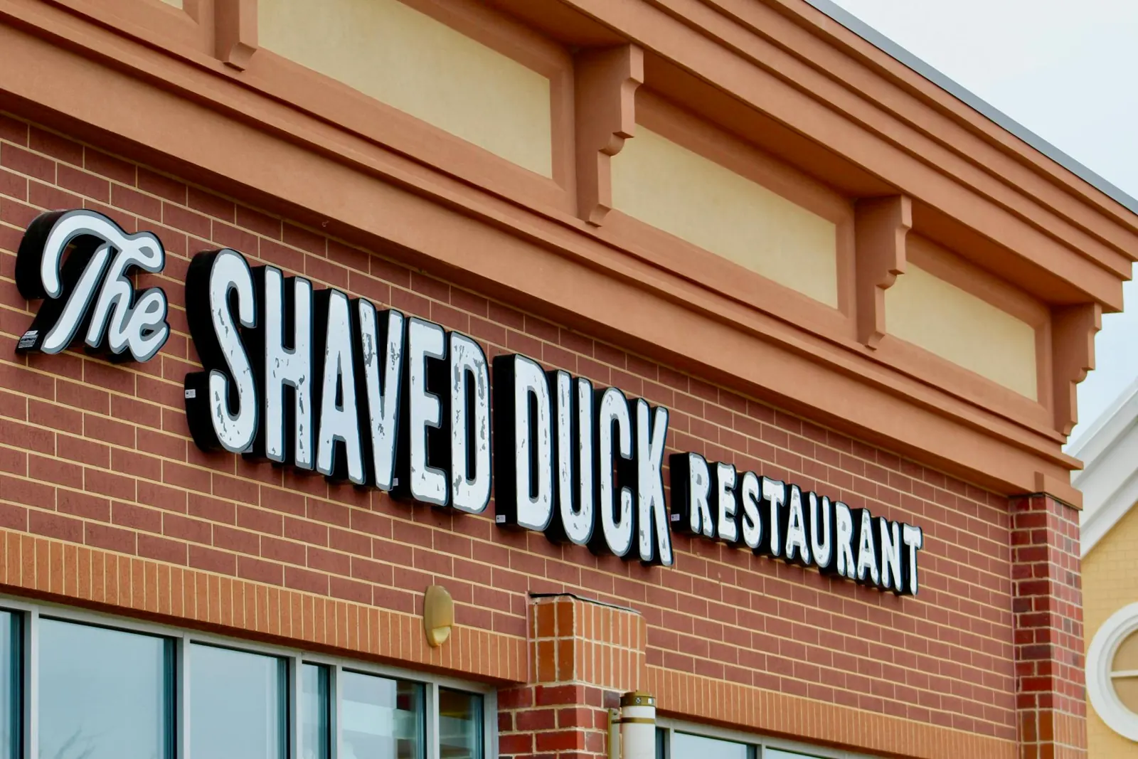 The Shaved Duck Restaurant sign above the brick storefront